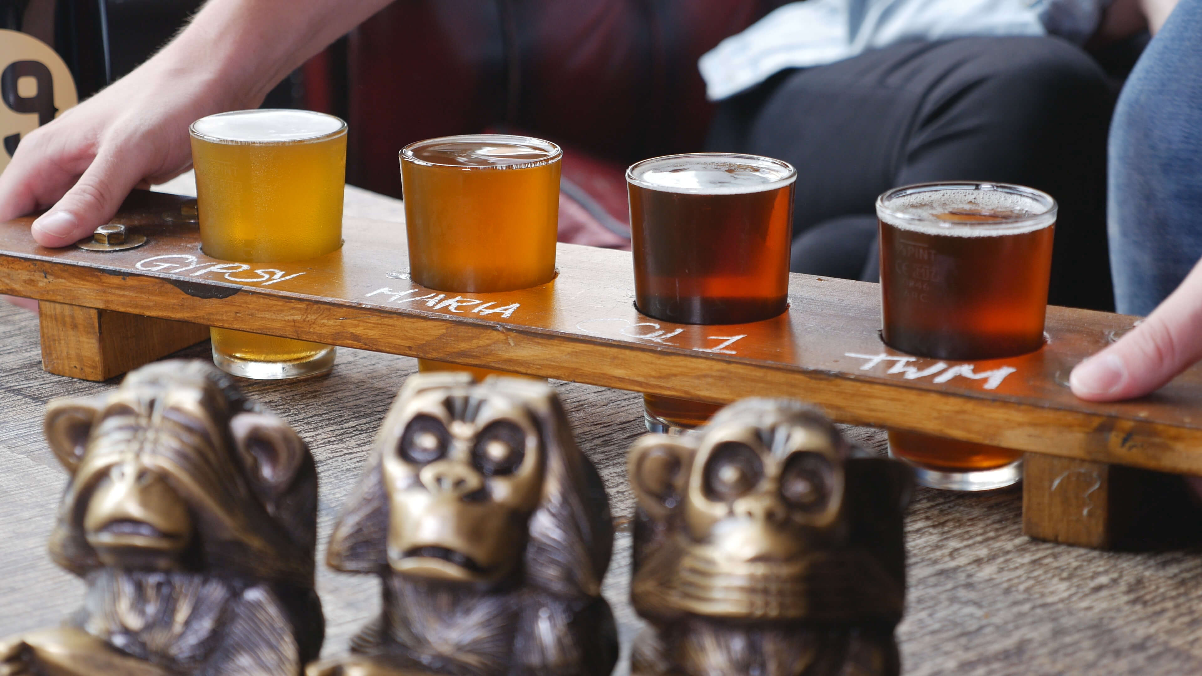 a wooden rack of 4 tasting beers from the three wise monkeys